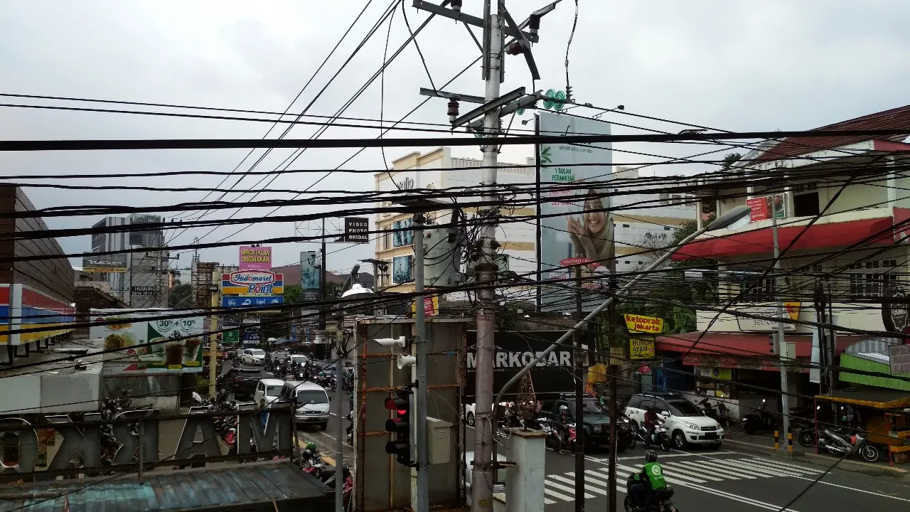 Lalu lintas dan pertokoan di Jalan Colombo Caturtunggal dengan jaringan kabel utilitas di atas jalan